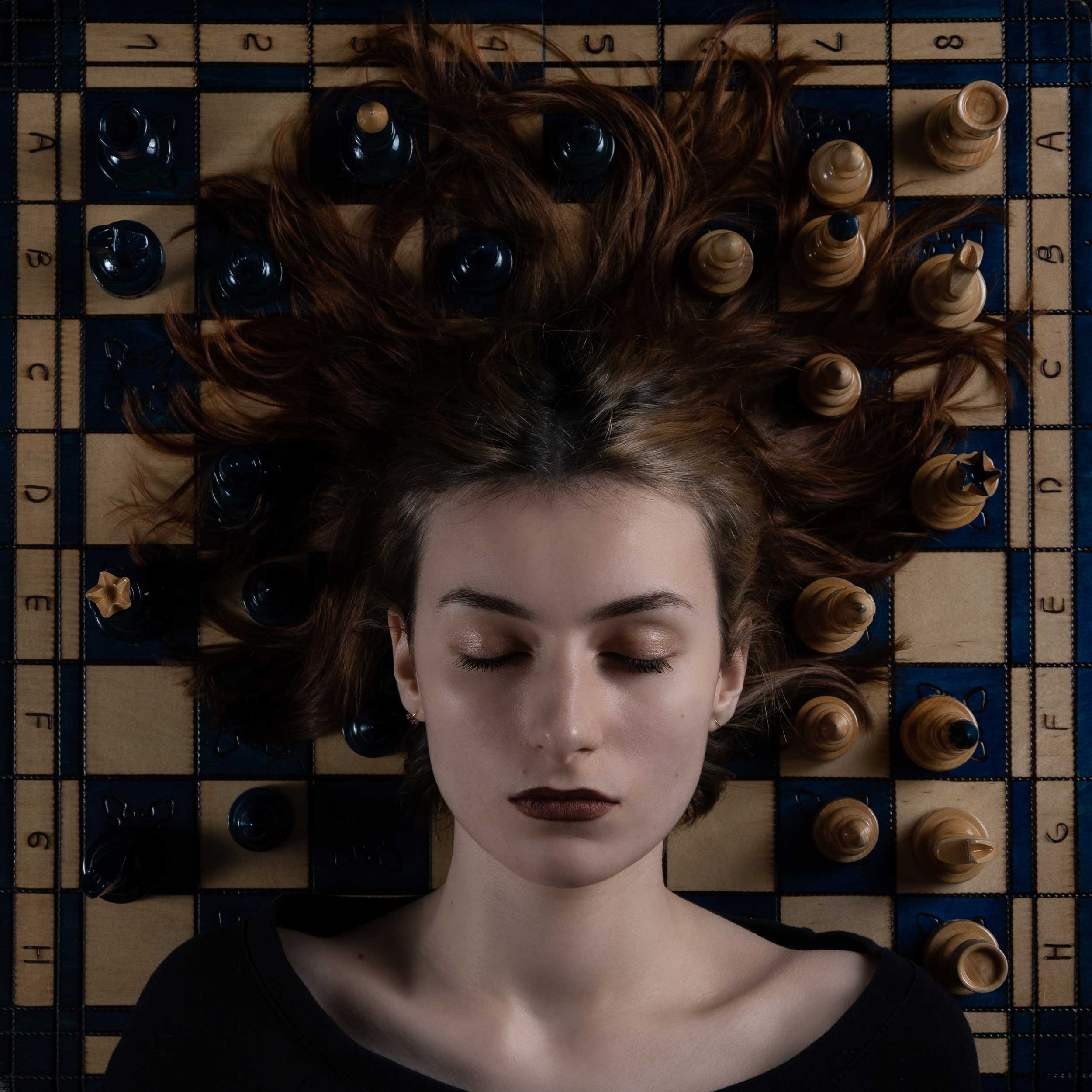 Ruda dziewczyna leży na szachownicy meduza