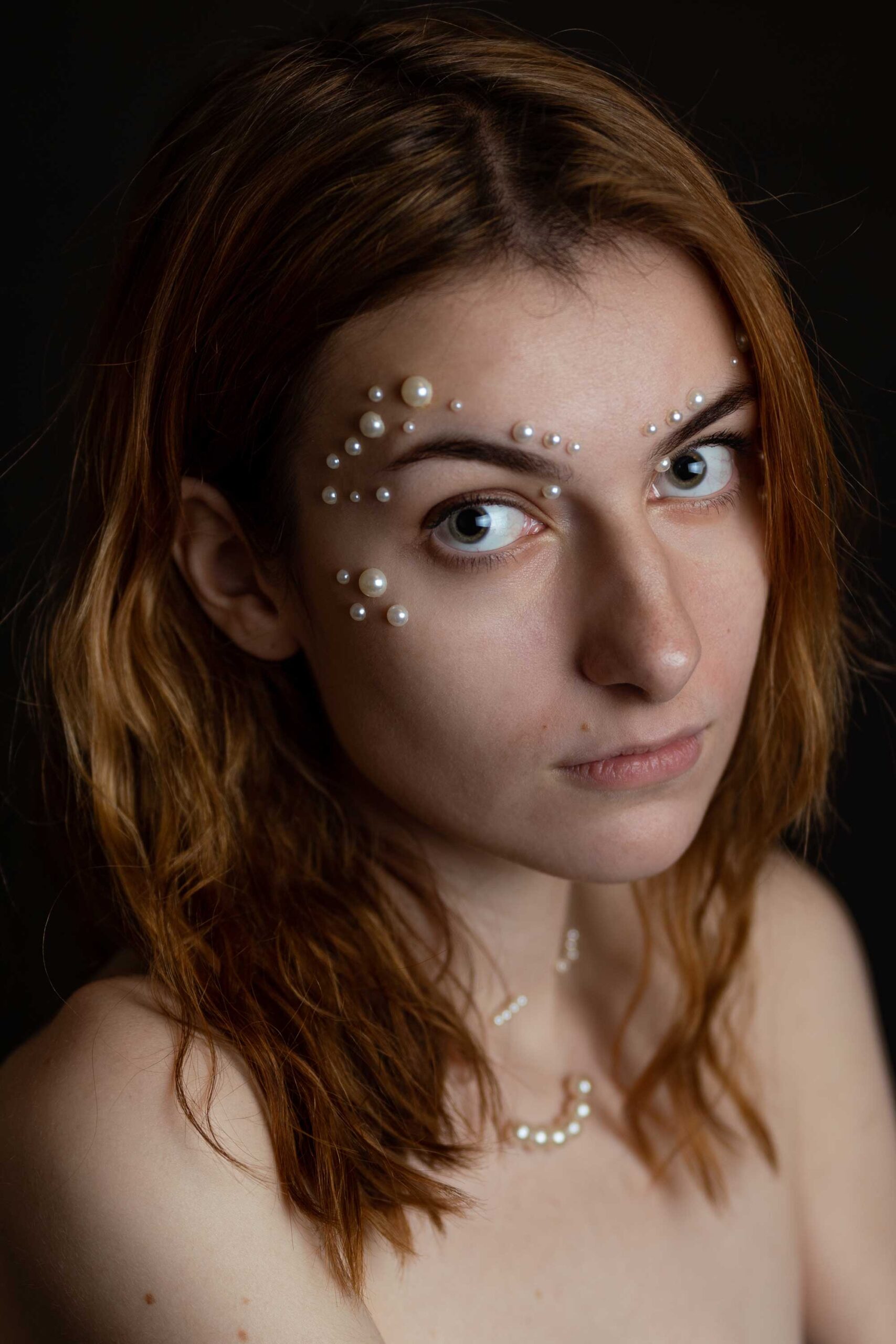 Ruda kobieta z perłami na twarzy. Bliski portret