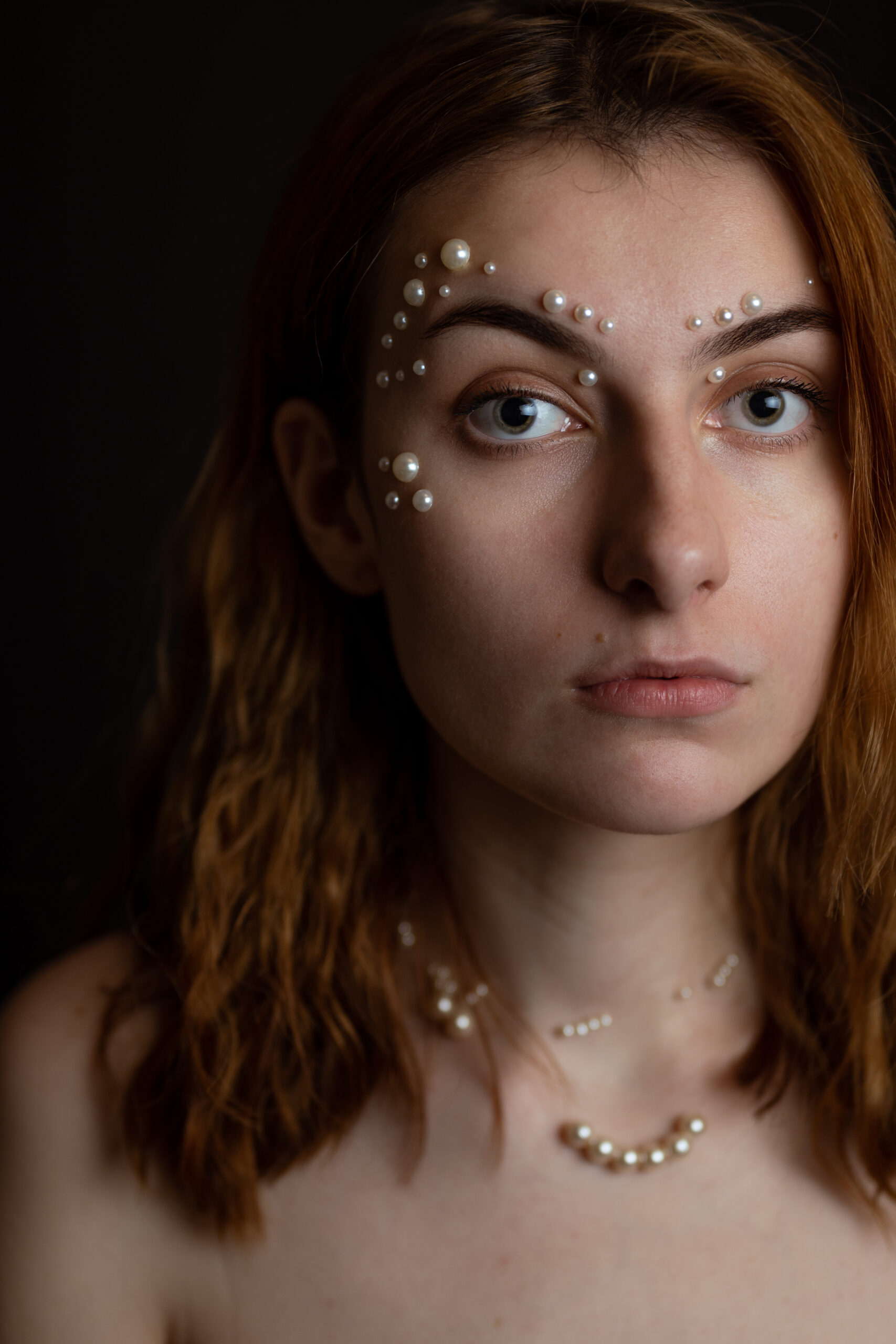 Ruda kobieta z perłami na twarzy. Bliski portret