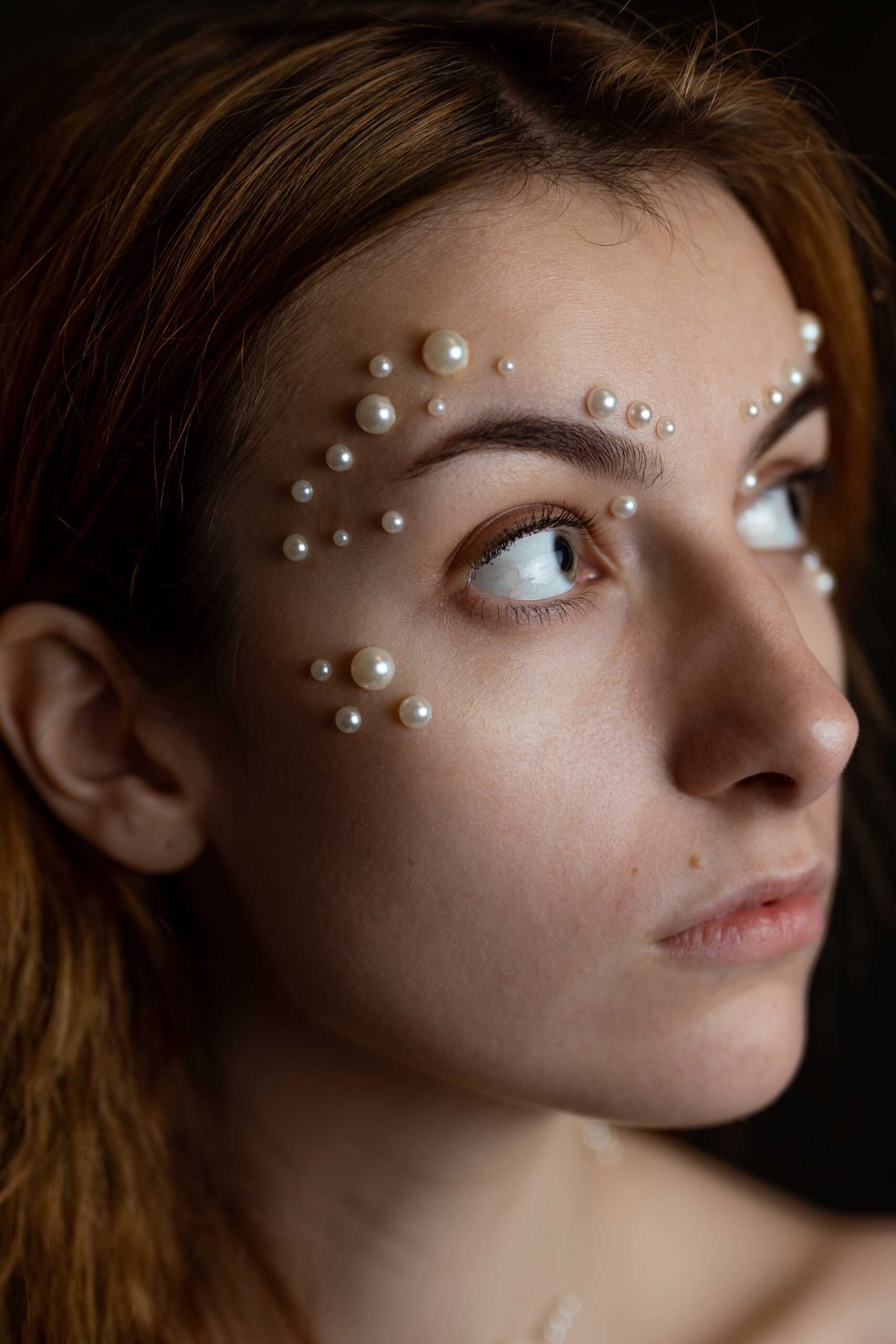 Ruda kobieta z perłami na twarzy. Bliski portret