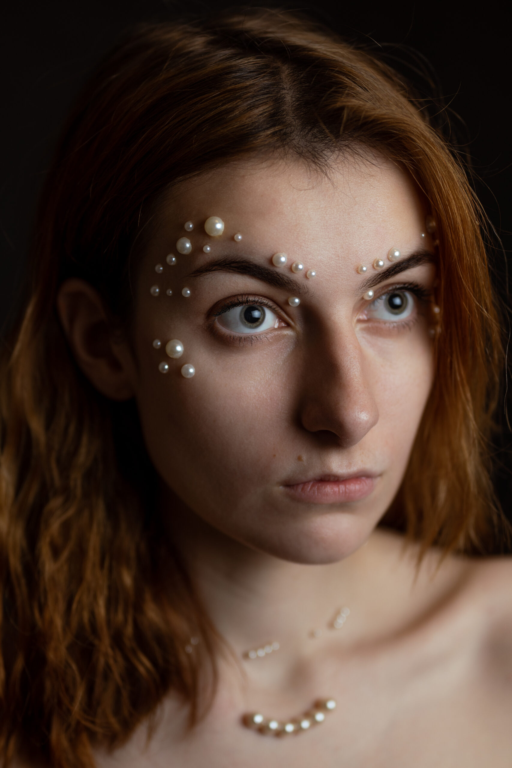 Ruda kobieta z perłami na twarzy. Bliski portret