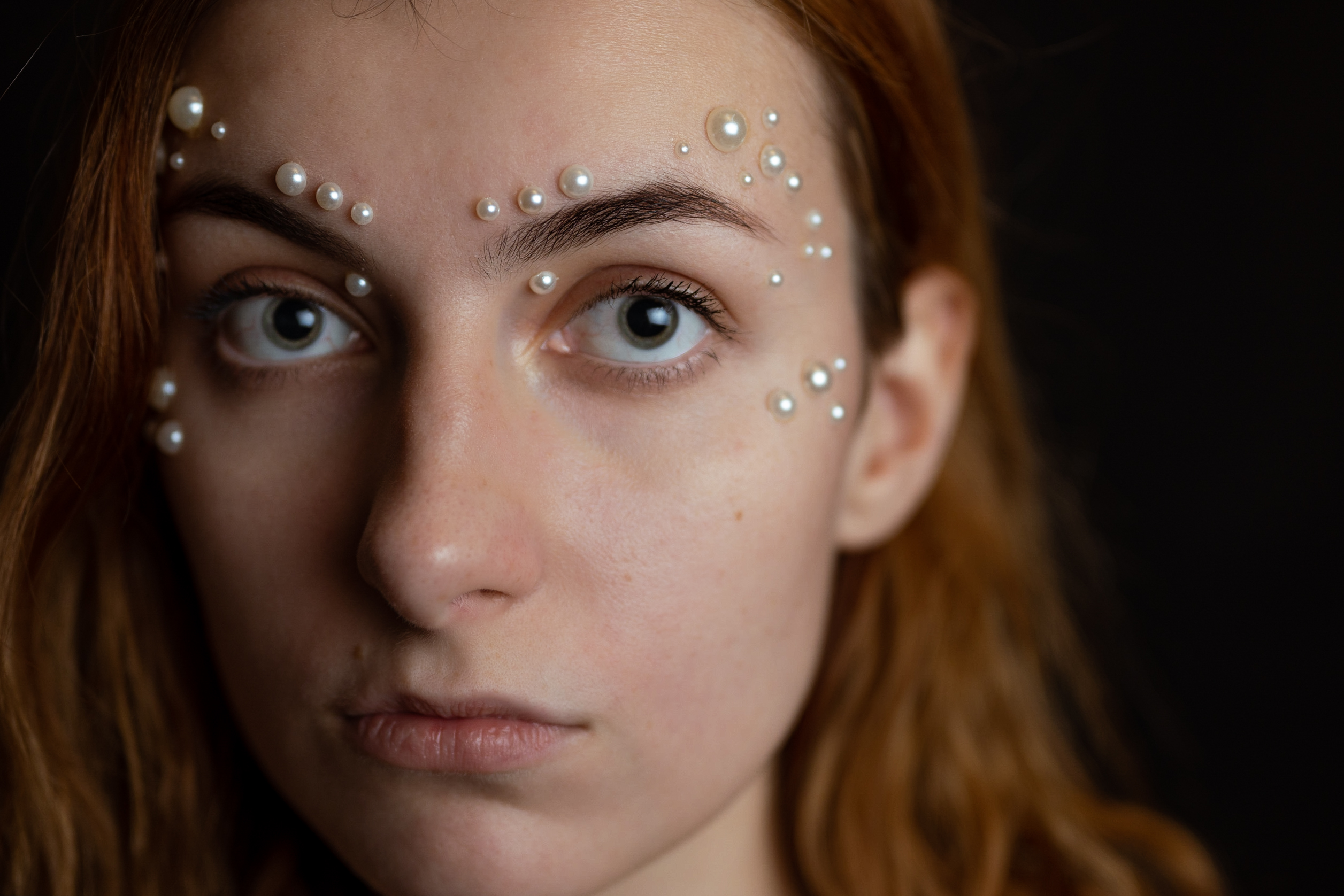Ruda kobieta z perłami na twarzy. Bliski portret