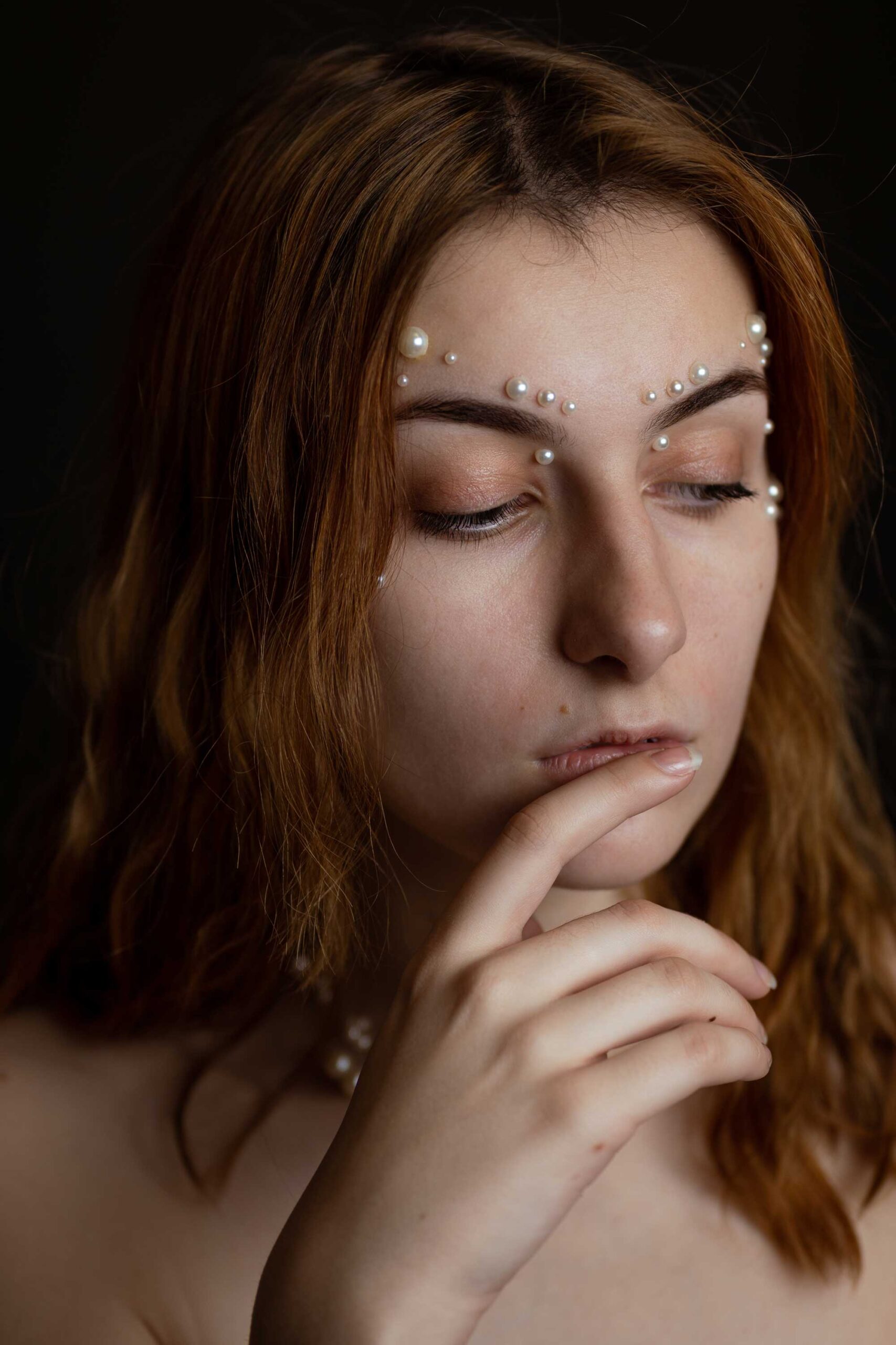 Ruda kobieta z perłami na twarzy. Bliski portret