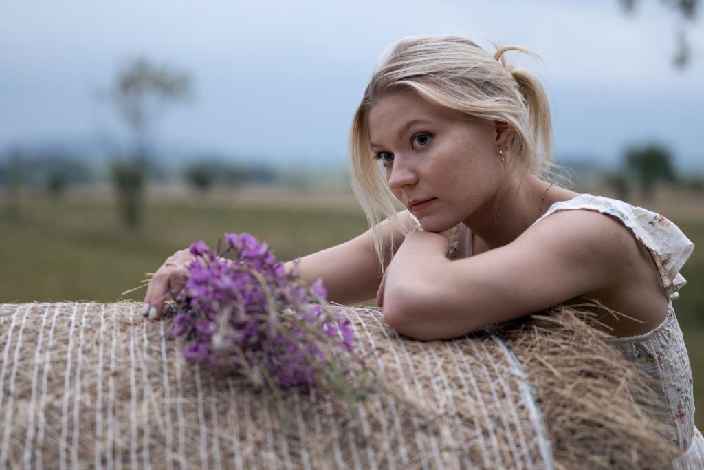 Dziewczyna z kwiatami na belce siana