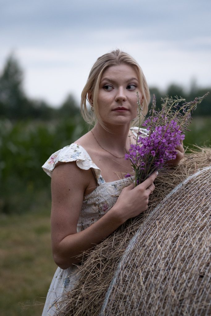 Dziewczyna z kwiatami na belce siana