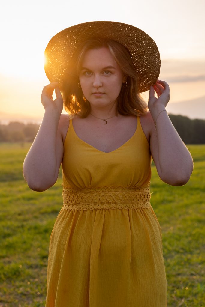 dziewczyna z kapeluszem stoi pod słońce o zachodzie słońca