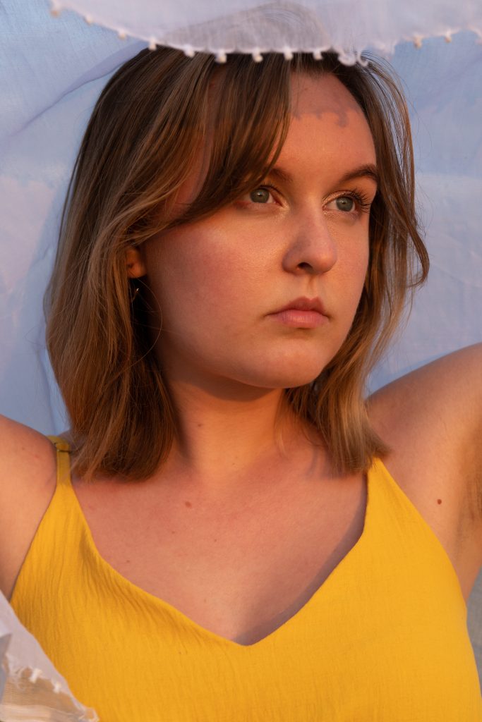 dziewczyna stojąca w zachodzie słońca z białą chusta nad głową