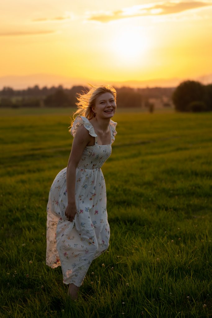 Dziewczyna tańcząca na łące o zachodzie słońca
