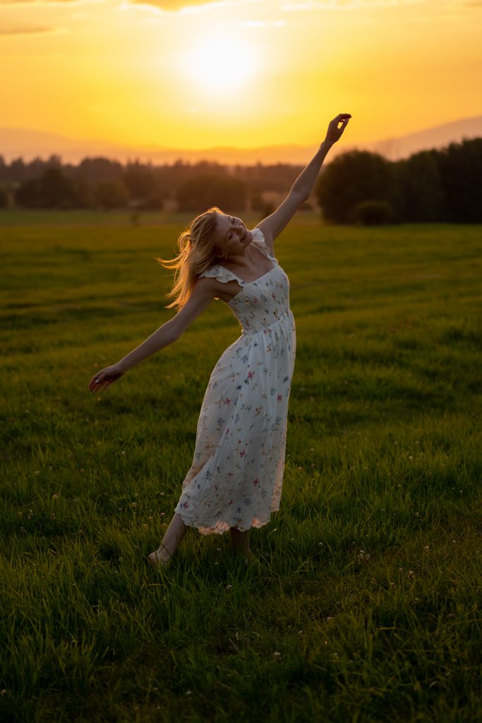 Dziewczyna tańcząca na łące o zachodzie słońca