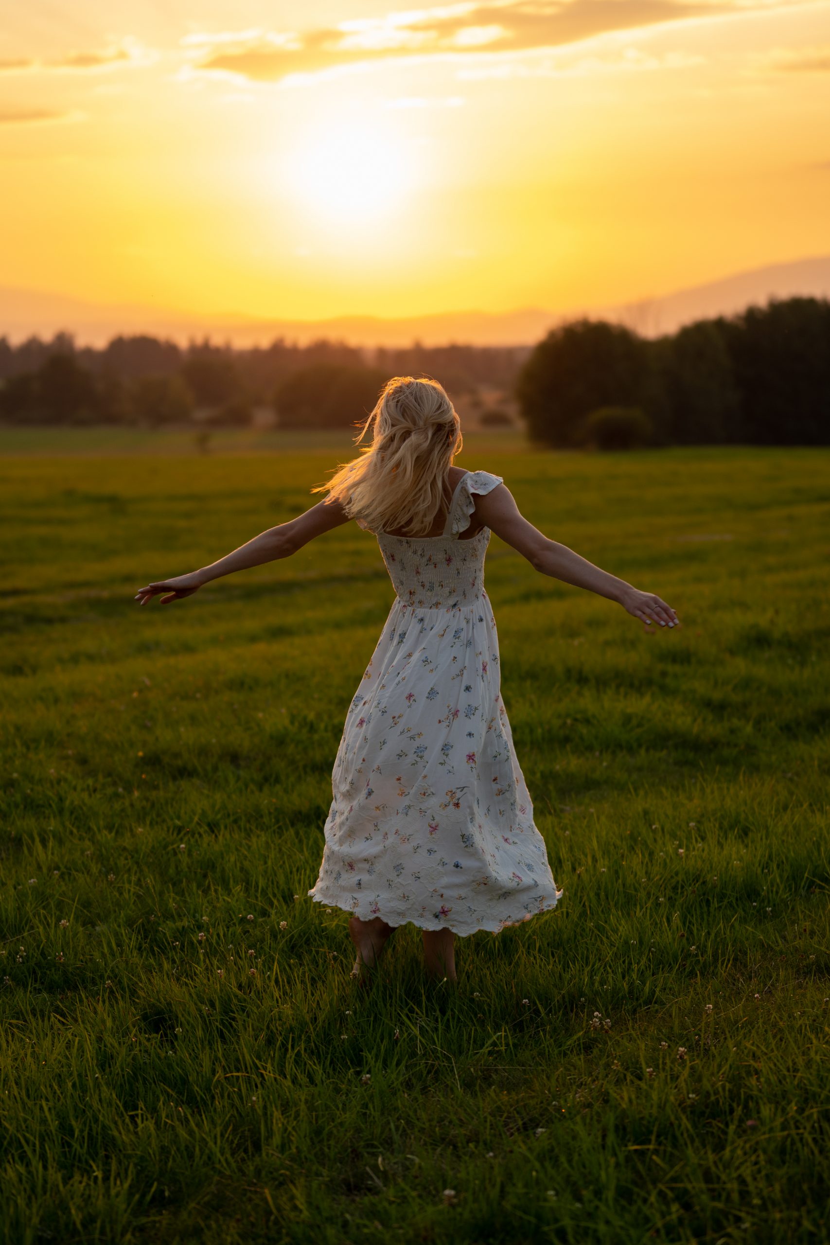 Dziewczyna tańcząca na łące o zachodzie słońca