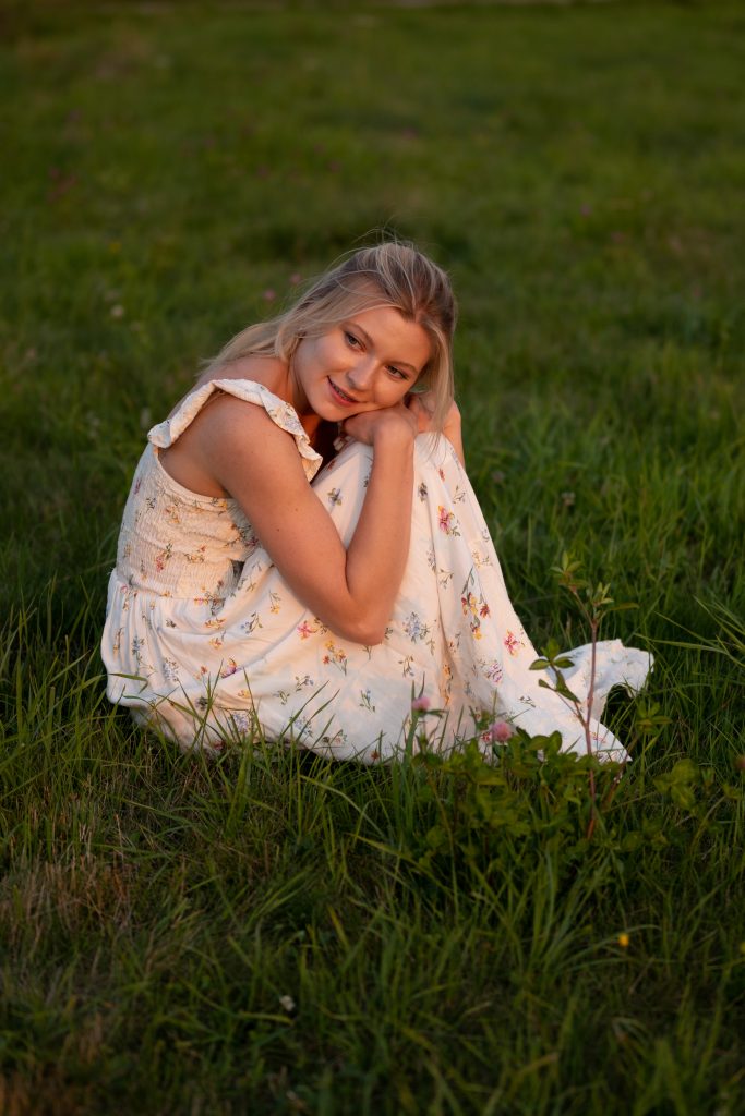 Dziewczyna siedząca na łące o zachodzie słońca