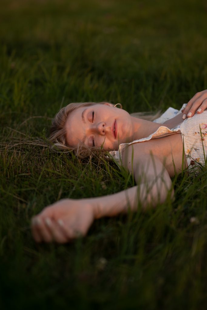 Dziewczyna leżąca na łące o zachodzie słońca
