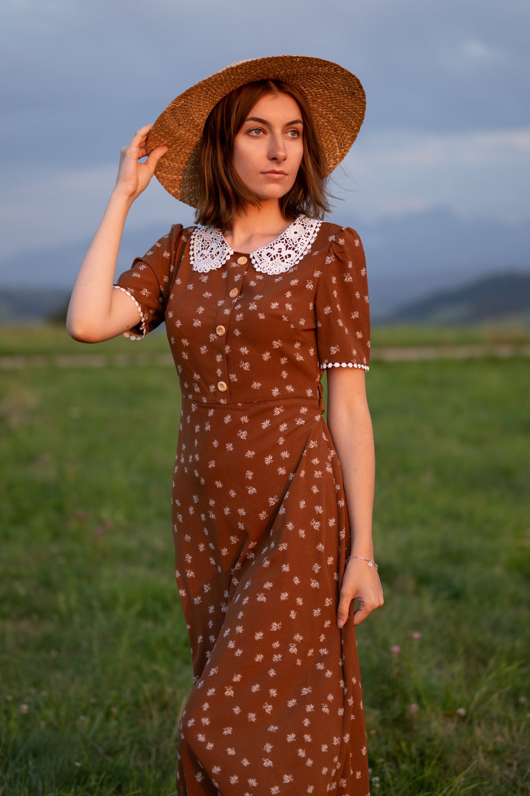 dziewczyna w sukience i kapeluszu stojąca w zachodzie słońca