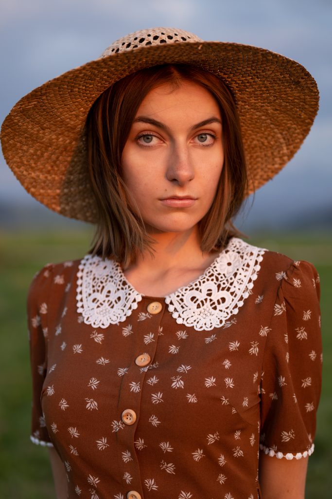 dziewczyna w sukience i kapeluszu stojąca w zachodzie słońca