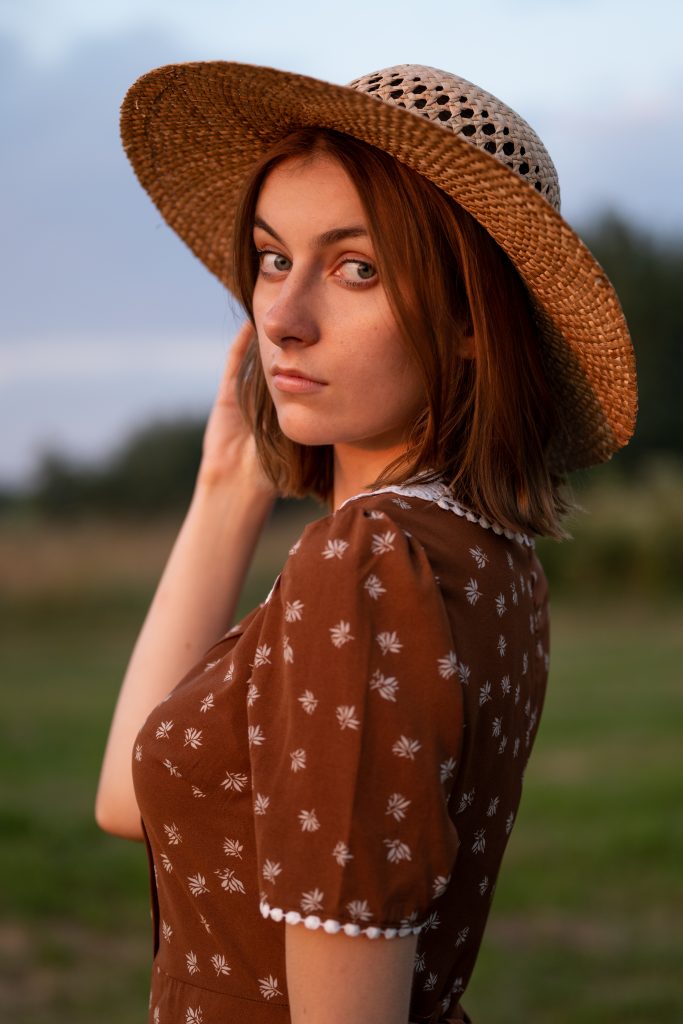 dziewczyna w sukience i kapeluszu stojąca w zachodzie słońca