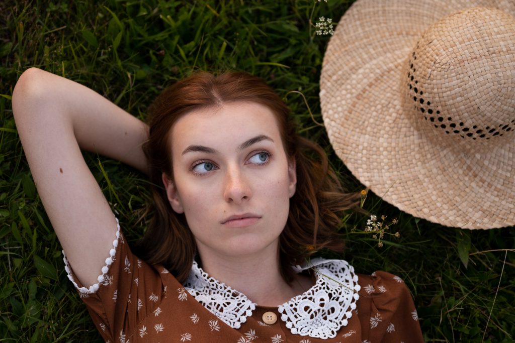 dziewczyna z kapeluszem leży na łące