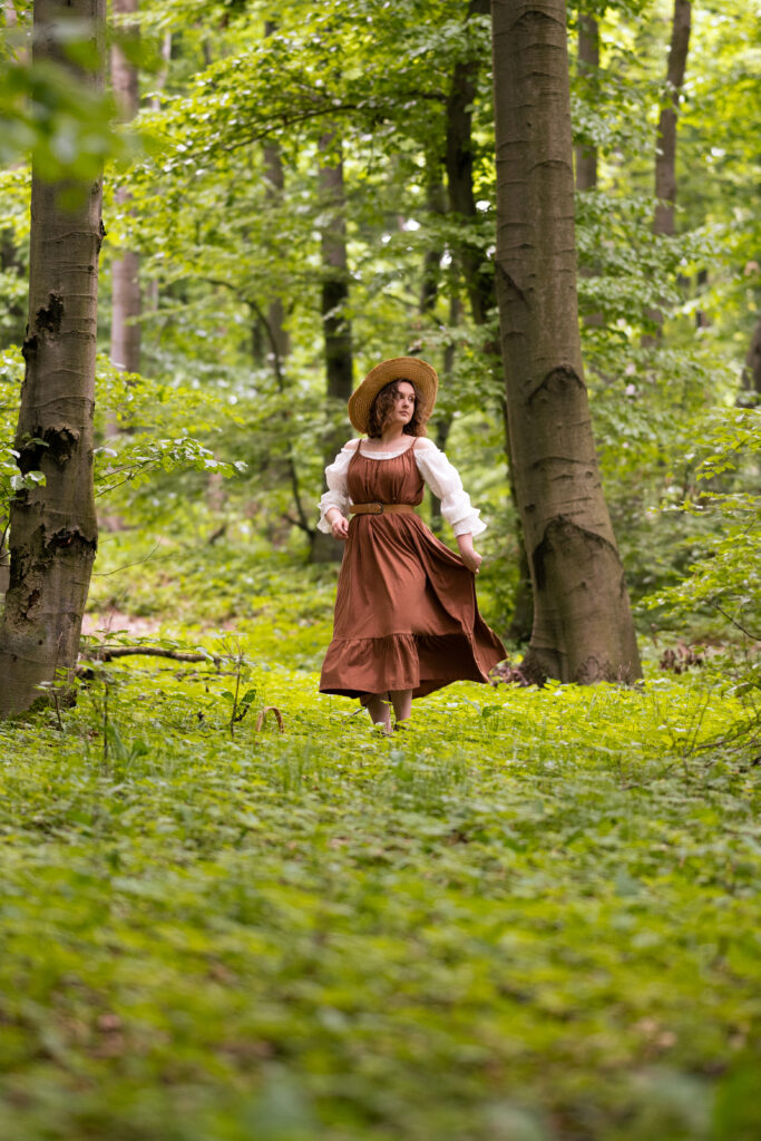 dziewczyna ubrana w brązową sukienkę znajduje się w lesie