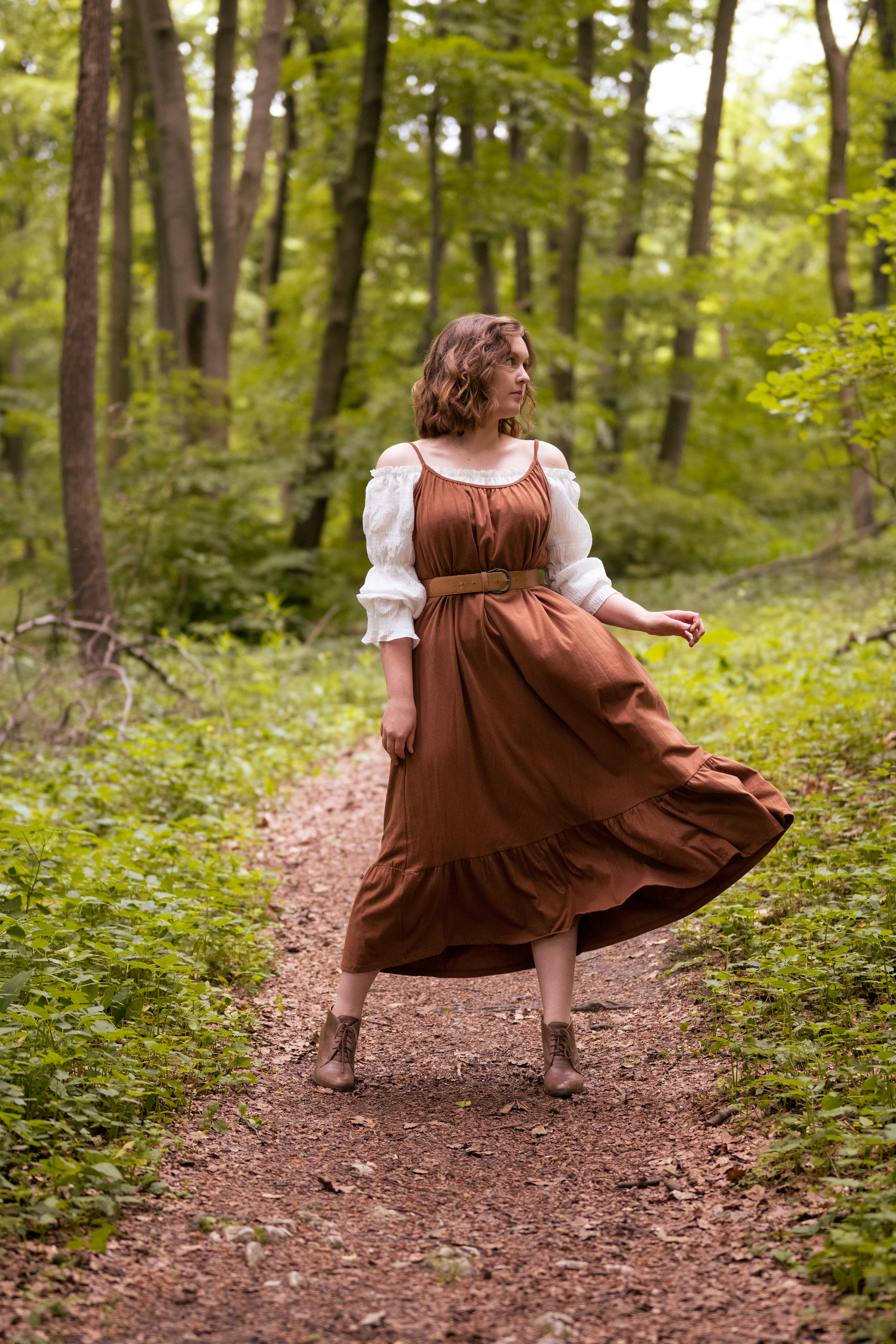 dziewczyna ubrana w brązową sukienkę znajduje się w lesie