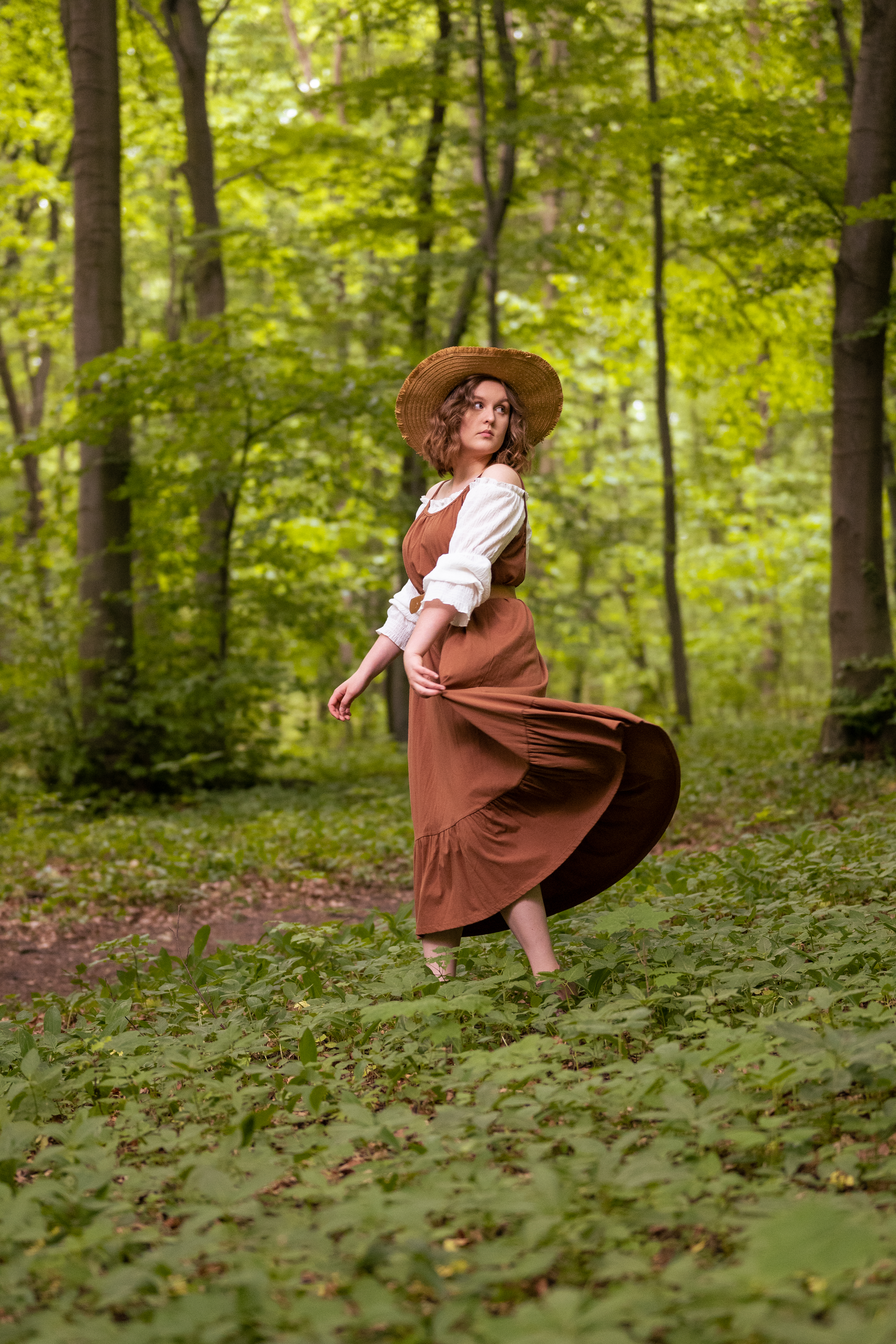 dziewczyna ubrana w brązową sukienkę znajduje się w lesie